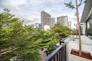 Un balcón con vista a un paisaje urbano, que incluye edificios altos y abundante vegetación.