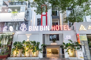 Exterior del hotel Bin Bin, con una recepción, un gran logotipo con la letra 'B' y la dirección '128'.
