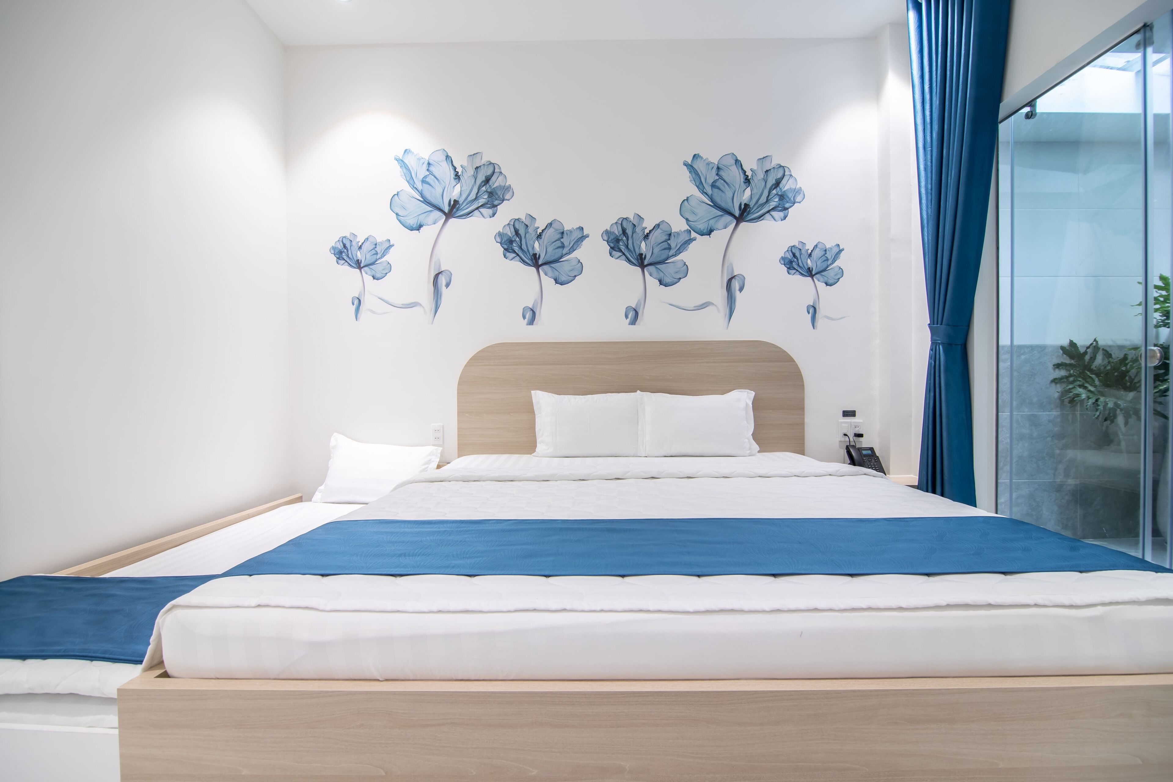Une chambre moderne avec un cadre de lit en bois, du linge de lit blanc et une touche de couleur bleue.