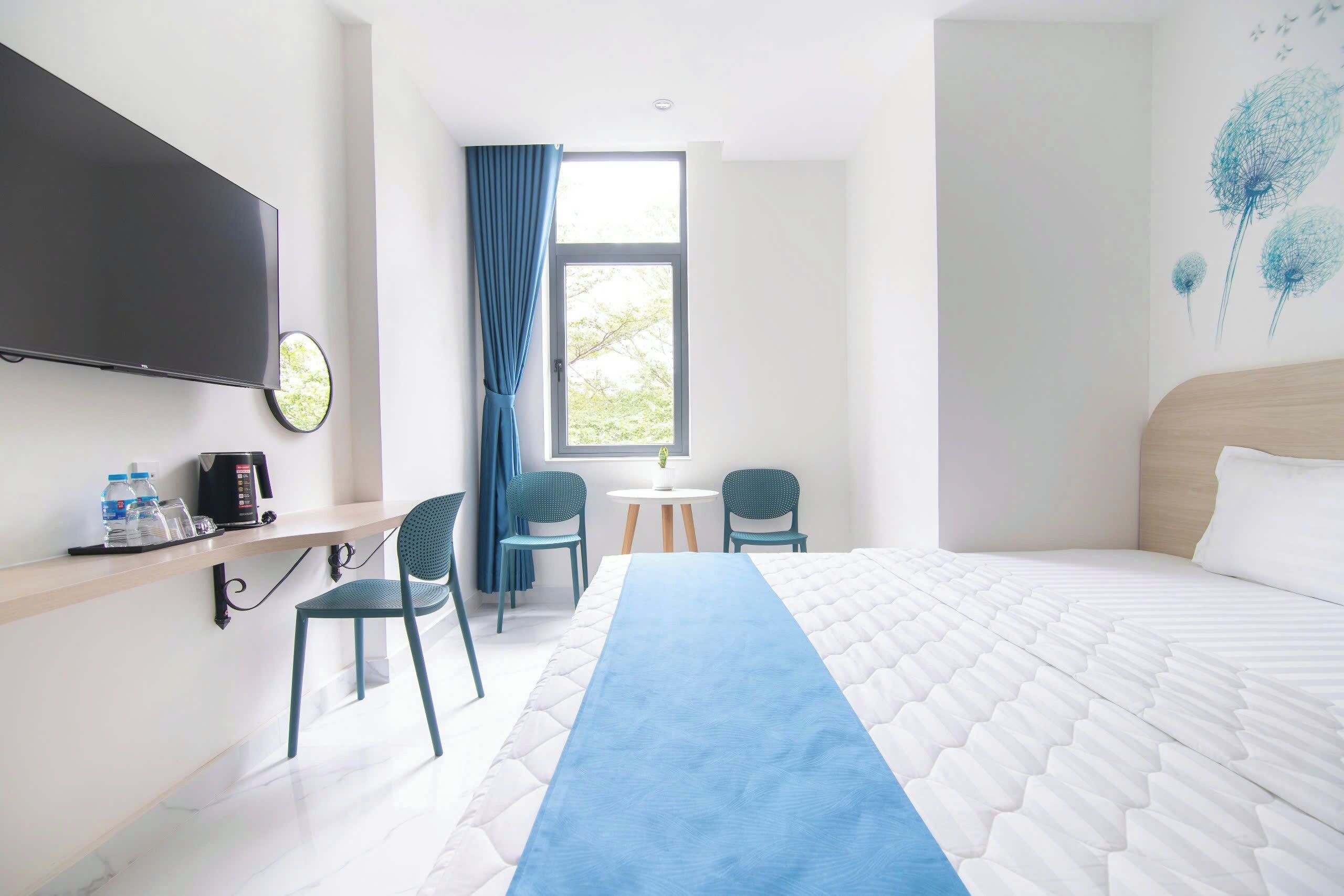 A hotel room with a bed, a desk with a TV, a coffee maker, and two chairs.