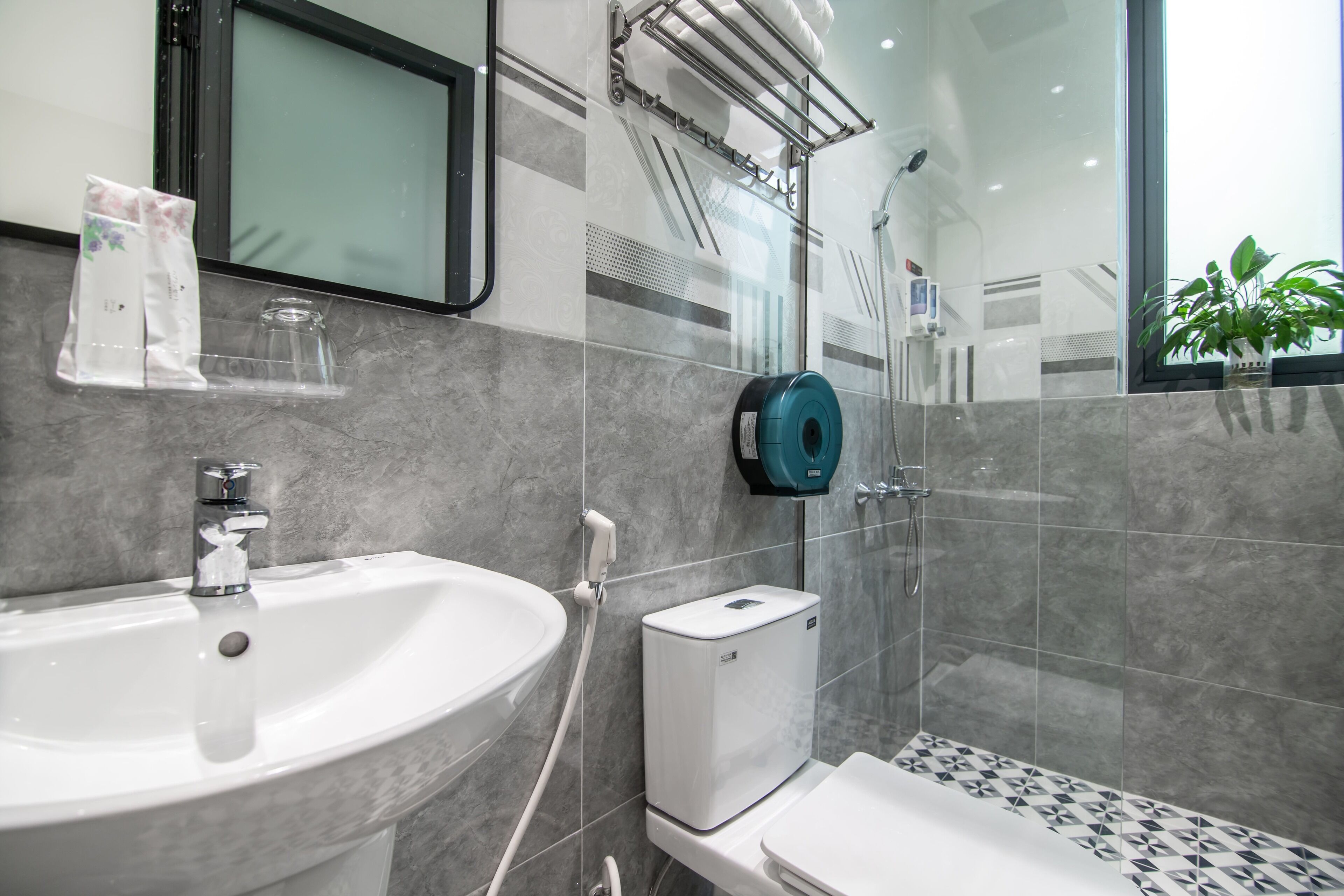 A modern bathroom with a white sink, a glass shower enclosure, and a toilet.