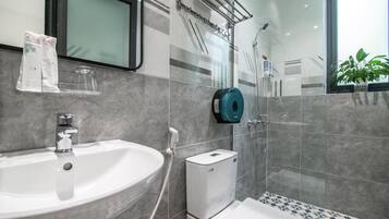 A modern bathroom with a white sink, a glass shower enclosure, and a toilet.