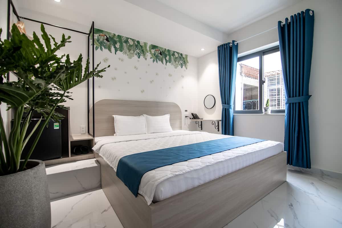 Ein modernes Schlafzimmer mit einem großen Bett, einem Topf mit Pflanze, einem Schreibtisch und einem Fenster mit Vorhängen.