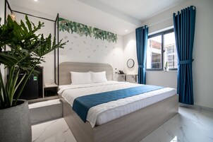 Un dormitorio moderno con una cama grande, una planta en maceta, un escritorio y una ventana con cortinas.