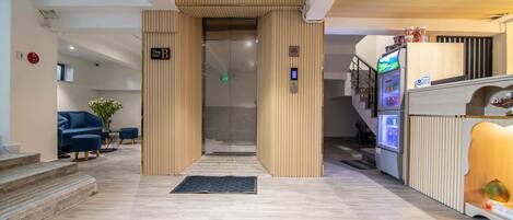 A modern lobby with a reception desk, a vending machine, and a staircase.