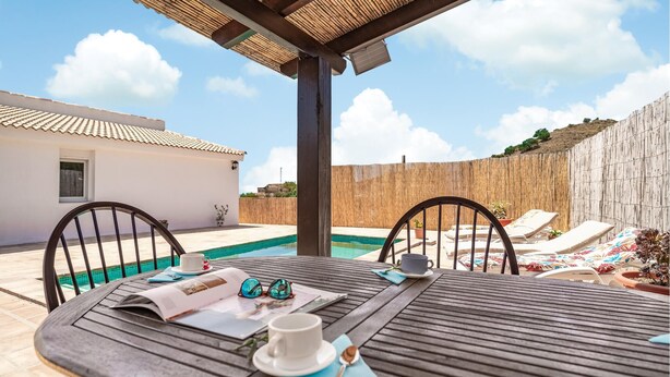A wooden table with a cup, sunglasses, and a menu, set against a poolside backdrop with lounge chairs and a wooden fence. - Beach front home in Benajarafe (Benajarafe)