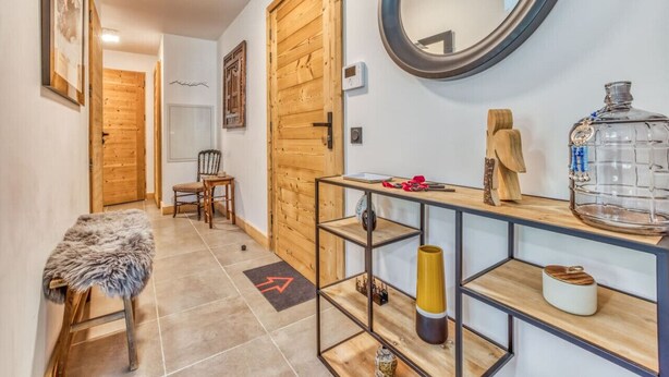 A hallway with wooden doors, a mirror, a console table with shelves, and a fur-covered bench. - Turra - Cosy 80m2 | Central | Remontée | Parking | Calme (Les Houches)