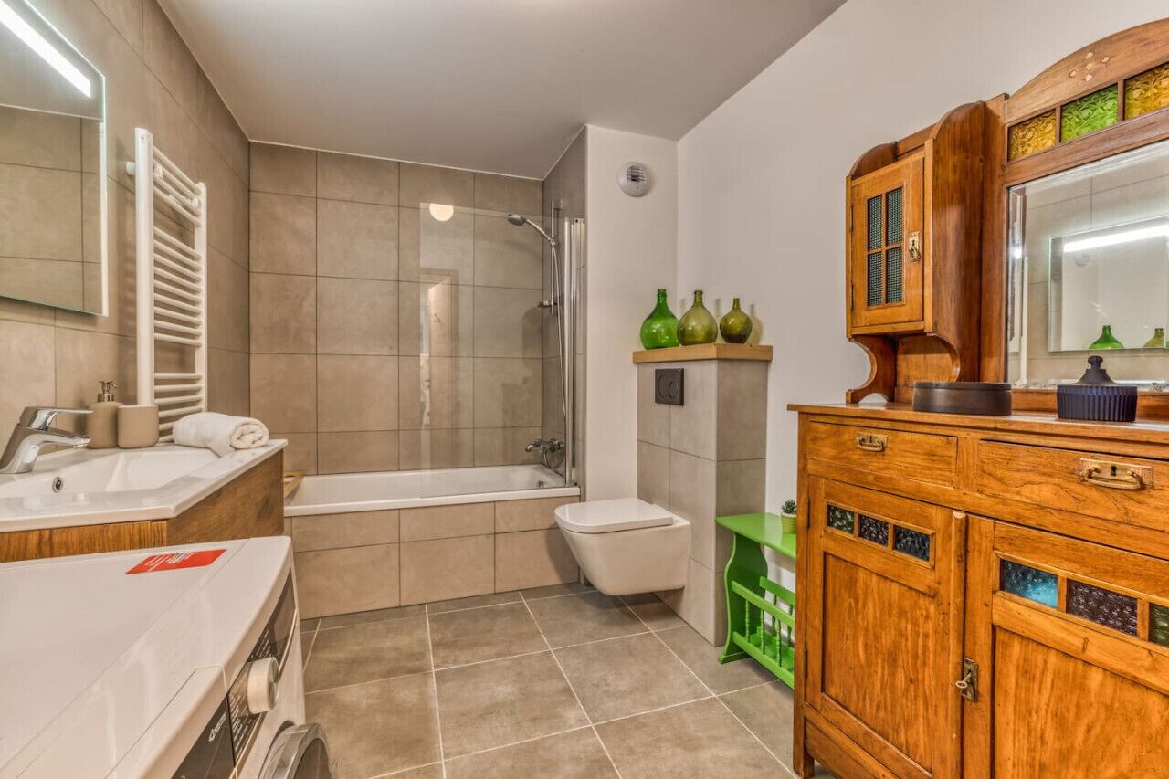 Een badkamer met een bad, toilet, wastafel en een badkamermeubel met spiegel.