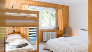 Un dormitorio con dos literas, una ventana con cortinas, un radiador y una silla.