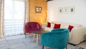 Una sala de estar con un sofá, dos sillones, una mesita y una ventana con cortinas.