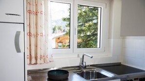 Una cocina con ventana, pileta de acero inoxidable y estufa.