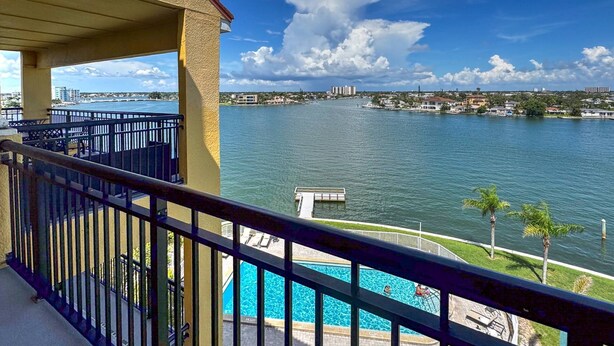 A balcony with a view of a lake, a dock, and a swimming pool.