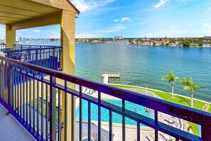 A balcony with a view of a lake, a dock, and a swimming pool.