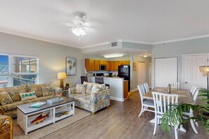 A living room with a sofa, coffee table, and a dining area with chairs and a table.