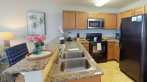 A modern kitchen with granite countertops, stainless steel appliances, and wooden cabinets.