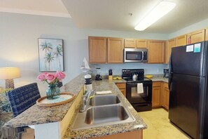 A modern kitchen with granite countertops, stainless steel appliances, and wooden cabinets.