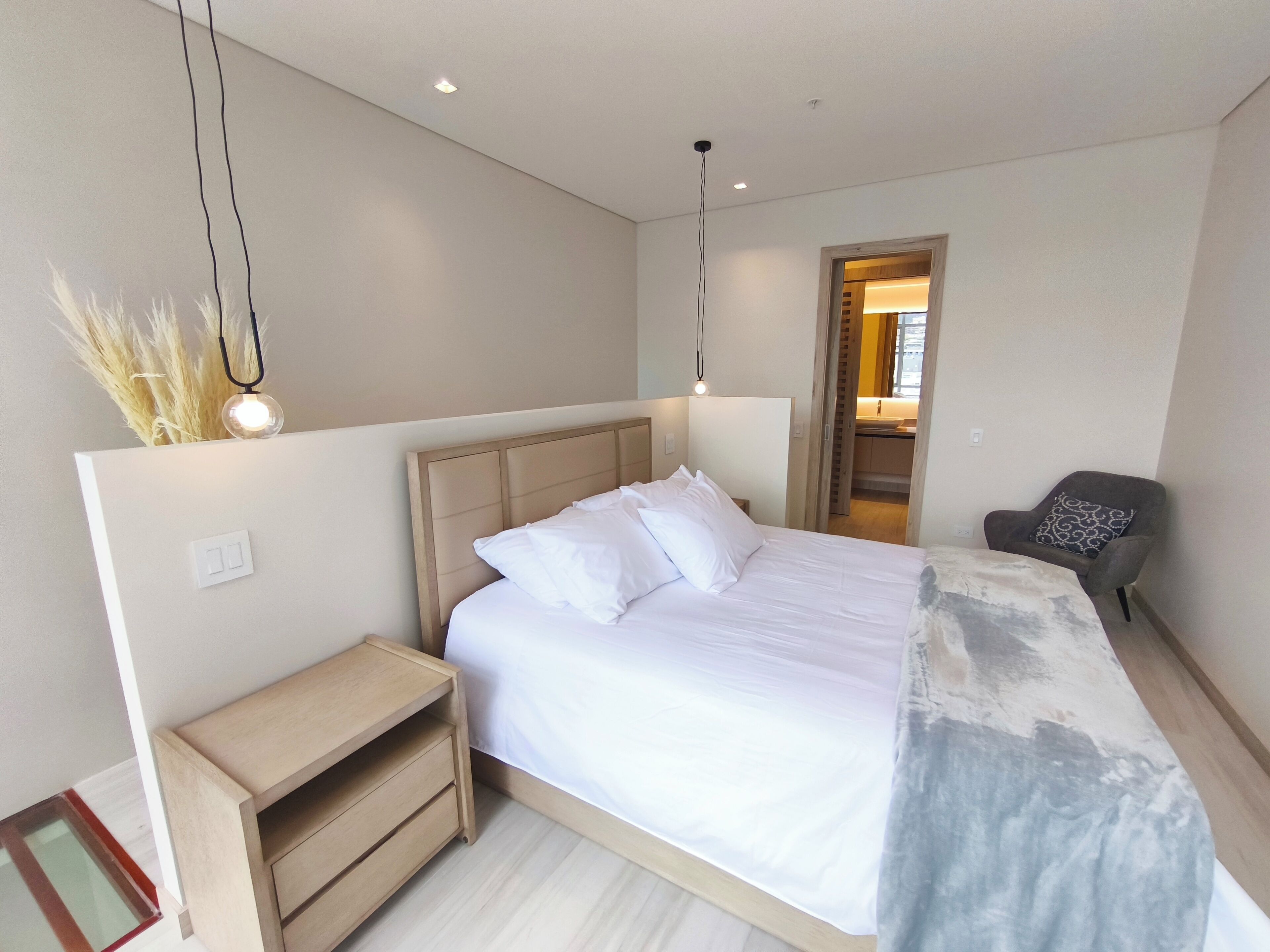 Un dormitorio moderno con una cama grande, mesitas de noche y una silla.