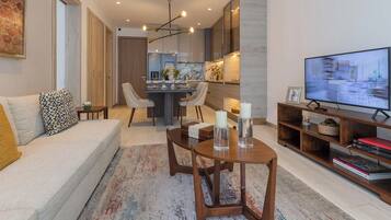 Una sala de estar moderna con un sofá, una mesa de centro, un televisor y una cocina al fondo.