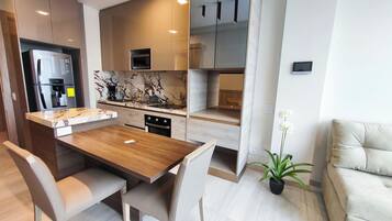 A modern kitchen with a wooden dining table and chairs, built-in appliances, and a marble backsplash.