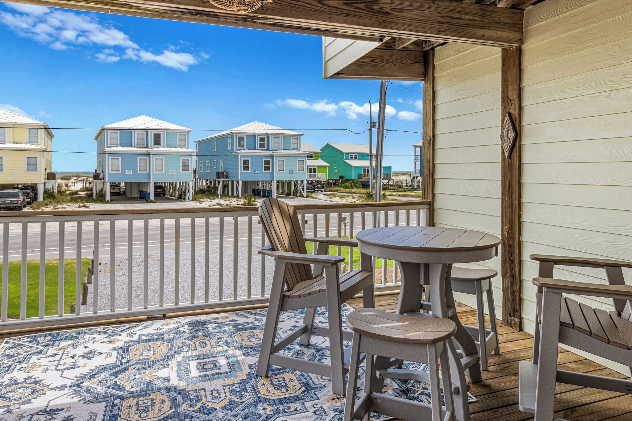 A porch with a patterned floor, wooden chairs, and a table.