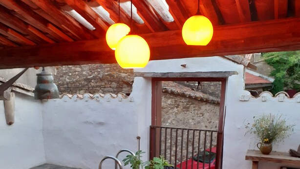 Un patio al aire libre con una mesa redonda, sillas de mimbre, una pequeña piscina y un coche rojo estacionado al fondo.