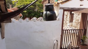 Una pequeña piscina al aire libre con una escalera metálica, rodeada por un muro blanco y una terraza de madera.