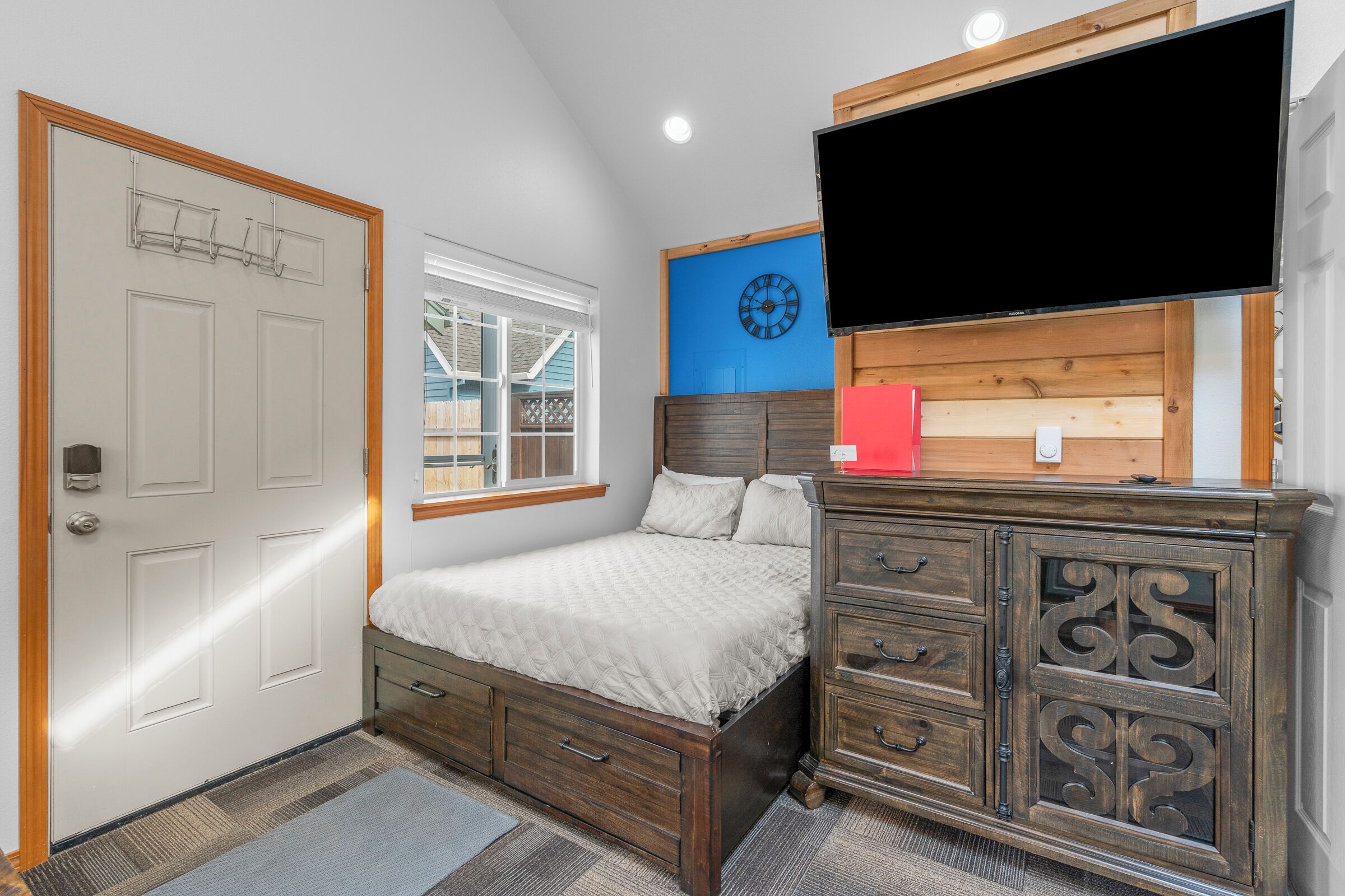 Une chambre à coucher avec un lit, une commode et un téléviseur fixé au mur.