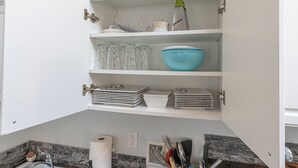 A kitchen with white cabinets, a marble backsplash, and a sink. - Cozy Tiny-Home with Big Heart! BBQ, 2Beds, WIFI, Pet Friendy! (Rockaway Beach)