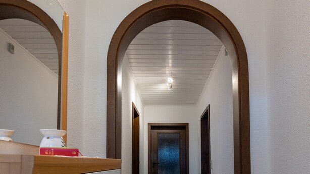 A hallway with a wooden bench, a radiator, and a door at the end. - Apartment 'Juttis Bude' with Private Terrace, Shared Garden and Wi-Fi (Löhnberg)