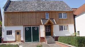 A two-story house with a front entrance, a garage, and a small front yard. - Apartment 'Ferienhaus Kaline' with Private Terrace, Private Garden and Wi-Fi (Grebenhain)