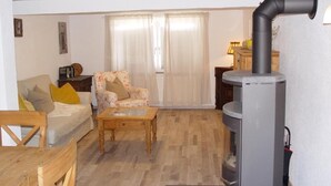 A cozy living room with a sofa, armchair, wooden coffee table, and a fireplace. - Apartment 'Ferienhaus Kaline' with Private Terrace, Private Garden and Wi-Fi (Grebenhain)