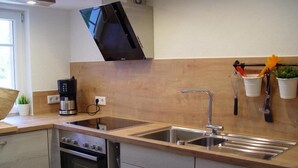 A kitchen with a double sink, a stove, and a microwave. There are cabinets and a countertop. - Apartment 'Ferienhaus Kaline' with Private Terrace, Private Garden and Wi-Fi (Grebenhain)