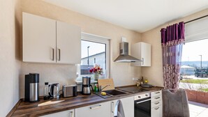 A modern kitchen with white cabinets, a stainless steel coffee maker, a toaster, and a sink. - 'Feel Free Apartment' holiday flat with private terrace and Wi-Fi (Rheinböllen)