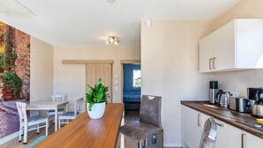 A modern kitchen with white cabinets, a wooden dining table, and bar stools. - 'Feel Free Apartment' holiday flat with private terrace and Wi-Fi (Rheinböllen)