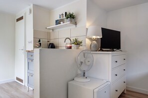 Une cuisine moderne avec des meubles blancs, une cuisinière encastrée, un four à micro-ondes et une machine à café.