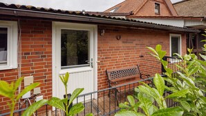 A brick house with a white door, a window, and a bench outside.