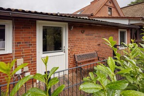 A brick house with a white door, a window, and a bench outside.