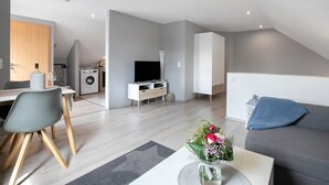 Un apartamento moderno con comedor, sala de estar con sofá, televisión y cocina.