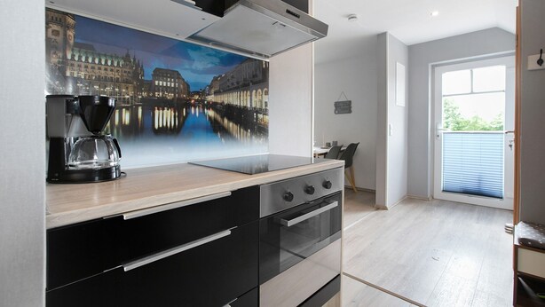 Una cocina moderna con un ventanal grande, una cafetera y un cuadro de un paisaje urbano.