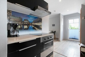 A modern kitchen with a large window, a coffee maker, and a painting of a cityscape.