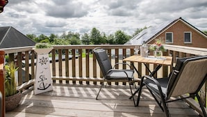 Una terraza de madera con una mesa, sillas, una maceta y un letrero decorativo.
