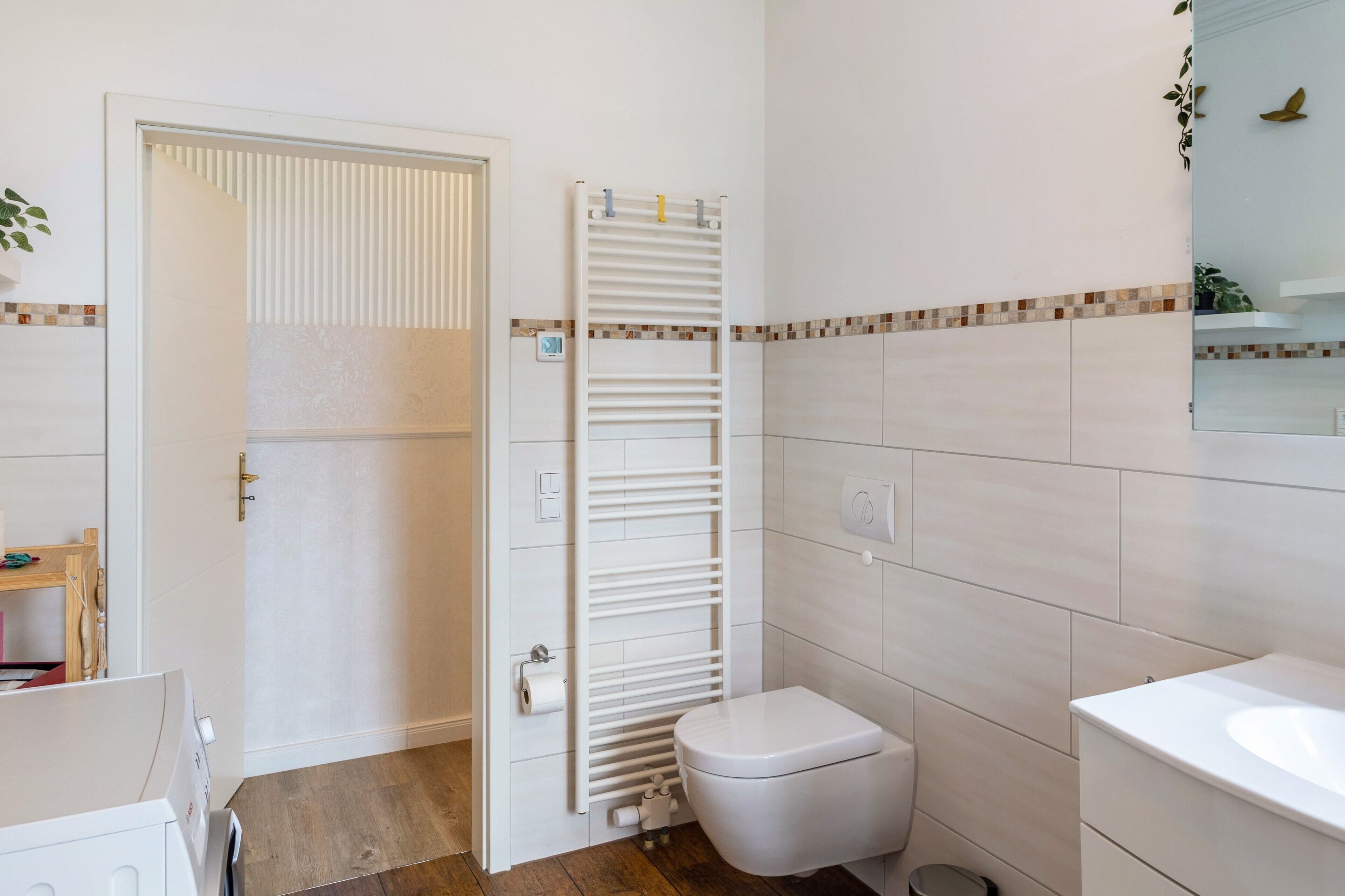 Une salle de bain comprenant des toilettes, un lavabo, un porte-serviettes et une porte.