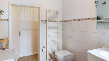 Une salle de bain comprenant des toilettes, un lavabo, un porte-serviettes et une porte.