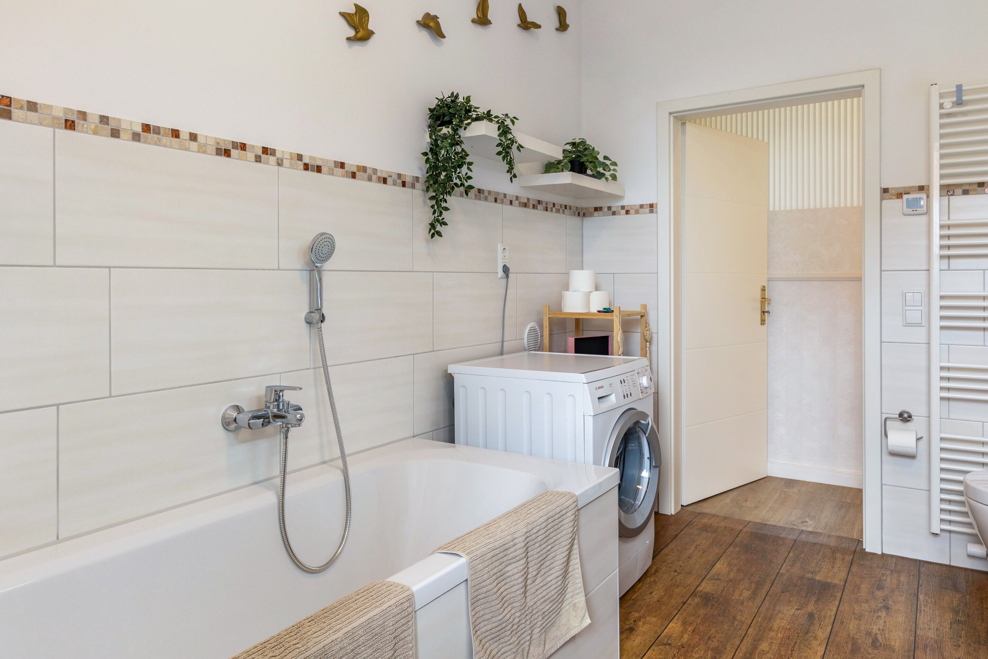 A bathroom with a bathtub, a washing machine, and a shower.