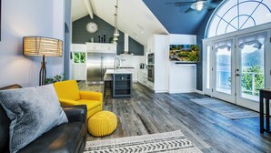 A modern kitchen with white cabinets, a stainless steel refrigerator, and a large window overlooking a balcony.