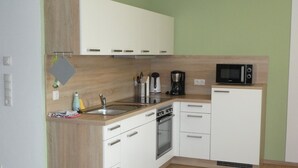 A compact kitchen with a sink, stove, microwave, and cabinets.