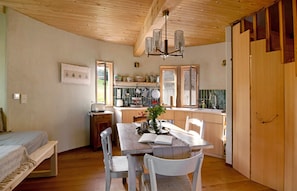 Cocina compacta con armarios de madera, una mesa y un banco.