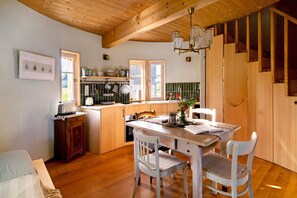 Un interior de madera con una mesa de comedor, sillas, una zona de cocina y una escalera.