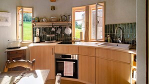 Eine Küche mit Holzausstattung, einem eingebauten Backofen, einer Spüle und einem Fenster mit Blick auf Grünflächen.
