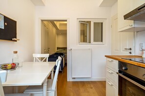 Una cocina compacta con una mesa, sillas, un radiador y una ventana.